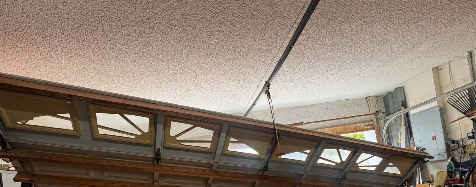 Sectional garage door hanging diagonally off its tracks inside a garage