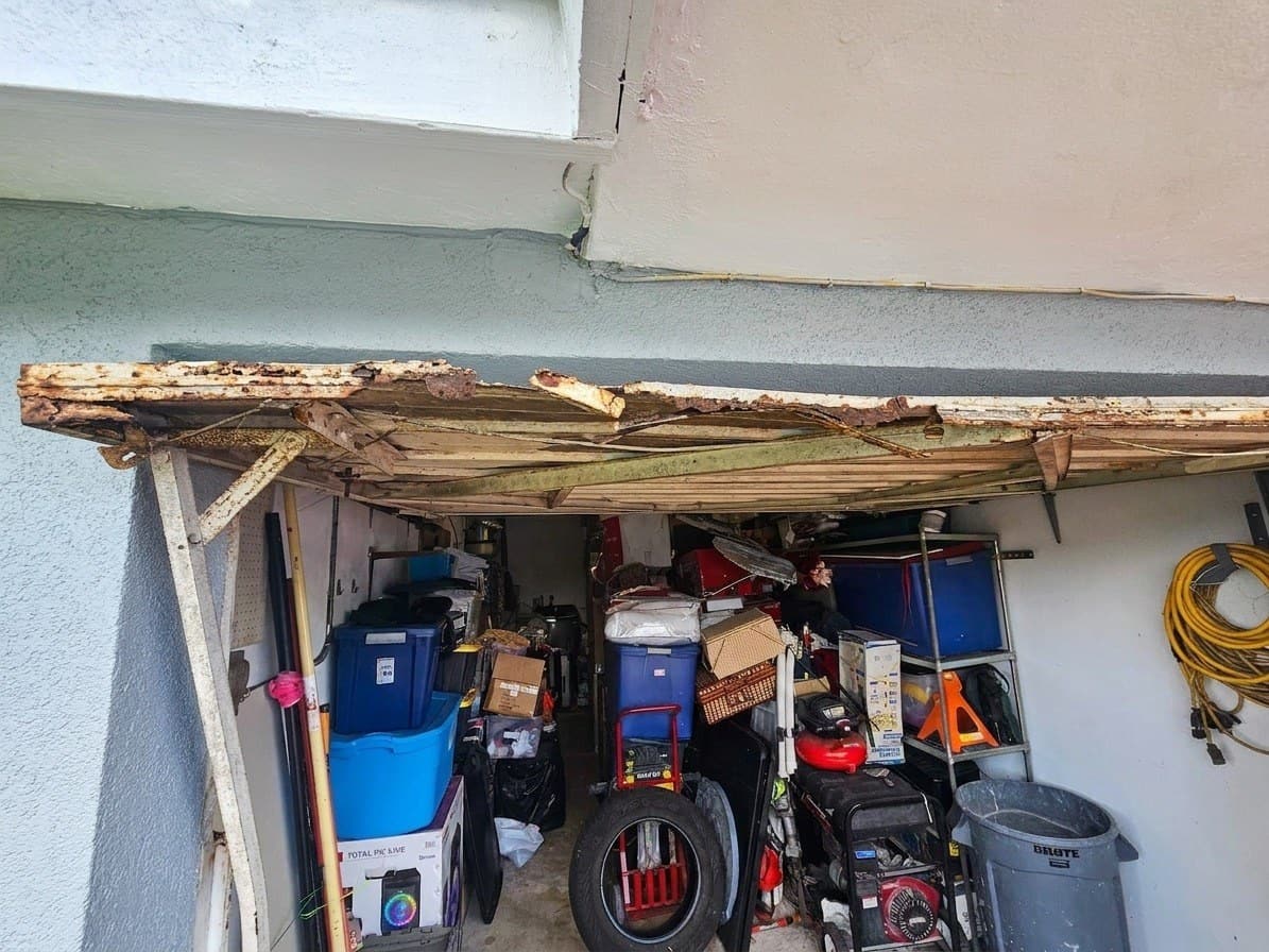 Dintel de madera podrido colapsando sobre la abertura de un garaje, puerta vieja retirada